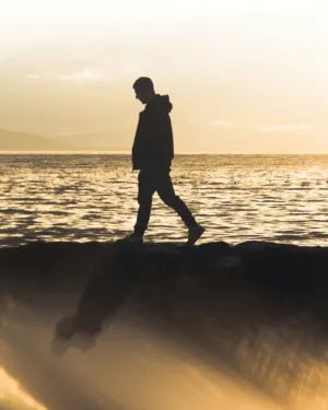 Silhouette Of A Man Walking By The Sea At Sunset