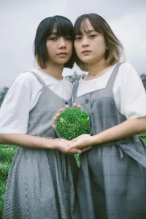 Two Girls Holding A Glass Ball With Grass