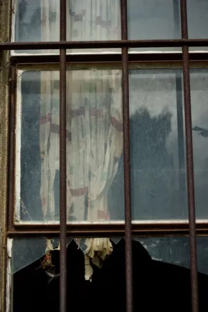 Rusty Window With Tattered Curtains