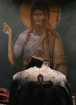 Priest Praying In Front Of Icon