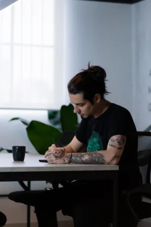 Tattooed Man Writing At Desk