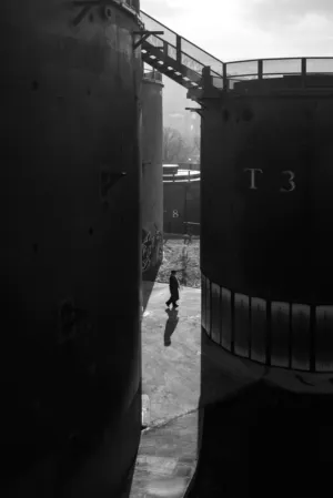 Silhouette Of A Person Walking Between Two Large Containers
