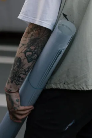 Tattooed Arm Holding A Rolled Document