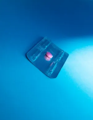 Single Pink Pill On Blue Background