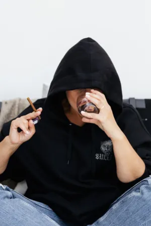 Person In Hoodie Drinking And Holding A Cigar
