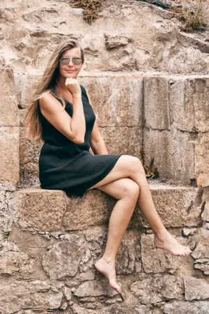 Woman In Black Dress Sitting On Stone Wall