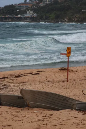 Beach With Boats And Warning Sign